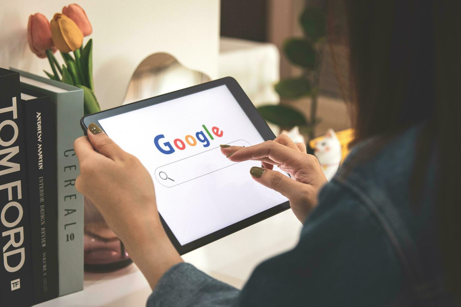 April 14, 2023 in Bangkok, Thailand. A woman holds iPad to search on Google website at Caf shop on holiday for news update source of information, entertainment media, news and articles photo