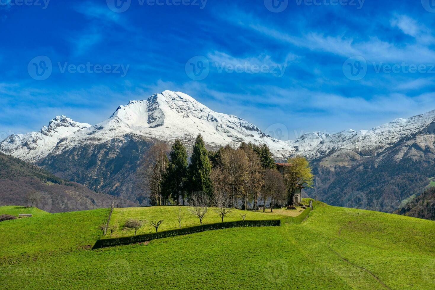 Hill in spring with snow capped mountains photo