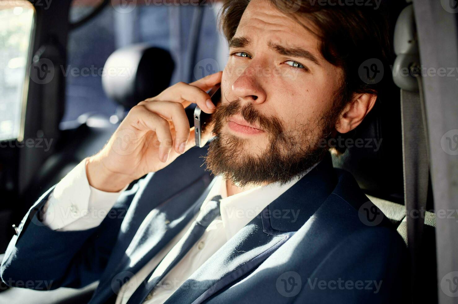 business man with a beard talking on the phone in a car trip photo