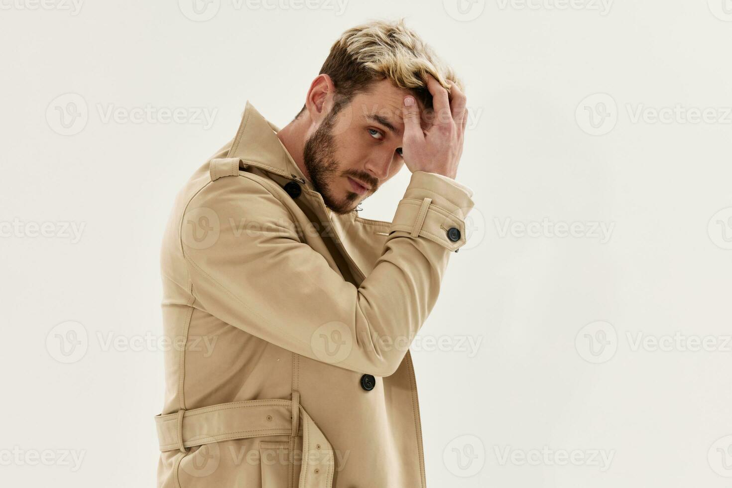 handsome man holding hand near head fashion coat autumn style isolated background photo