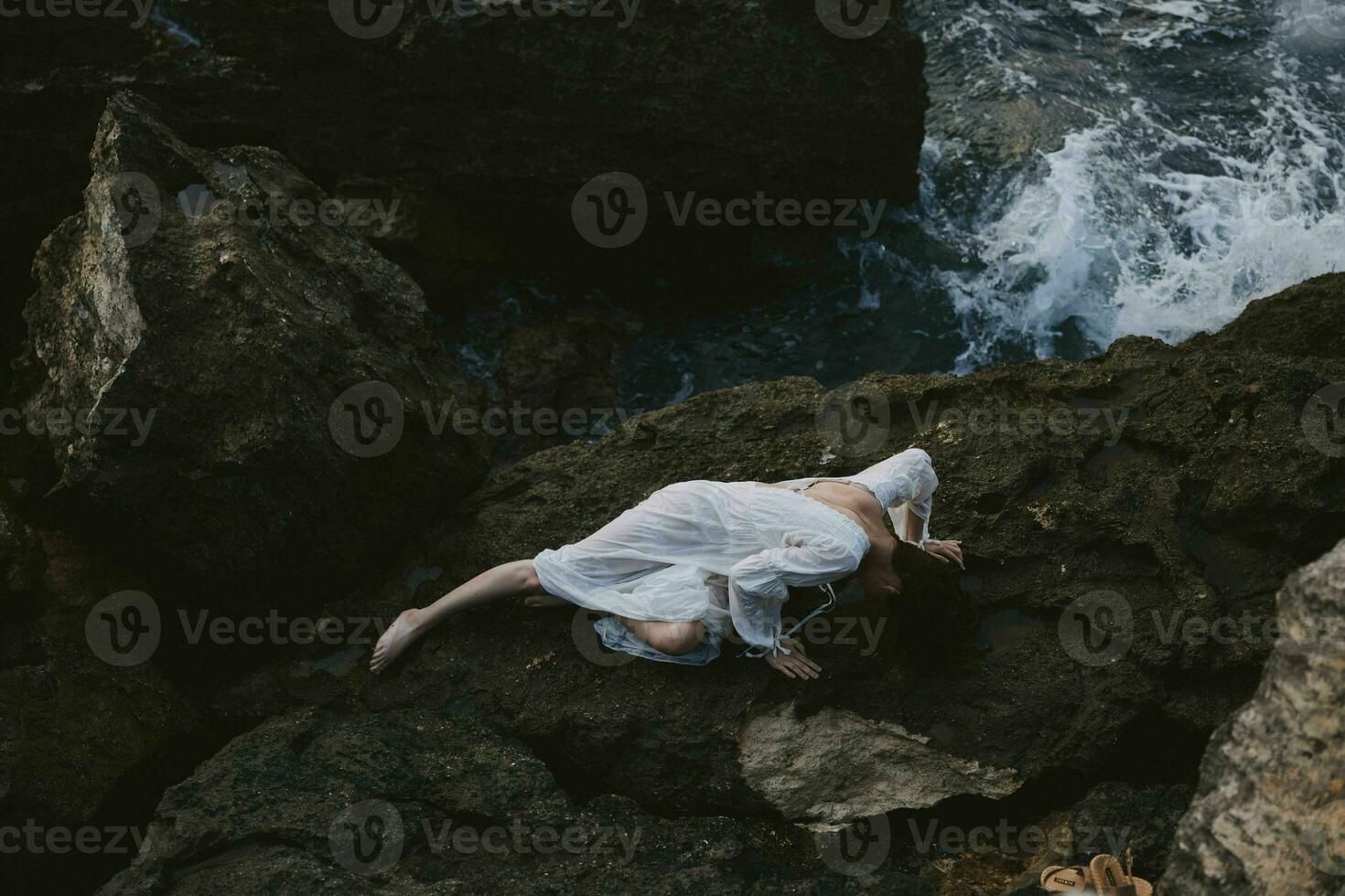 Beautiful bride lying on rocky coast with cracks on rocky surface landscape photo