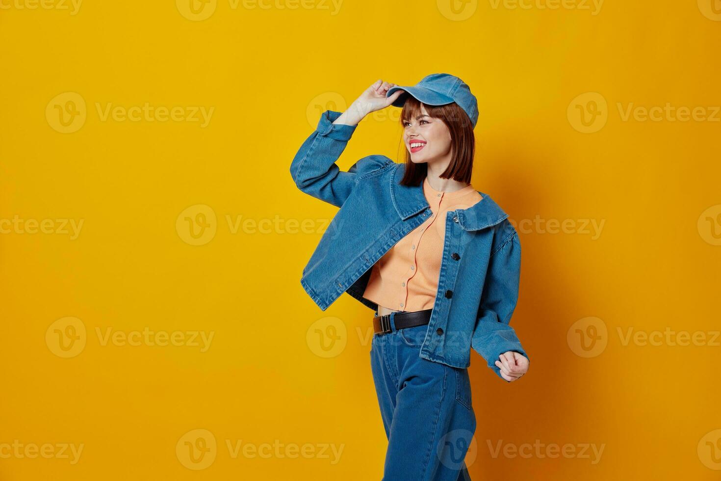 Pretty young female denim clothing fashion posing cap yellow background unaltered photo