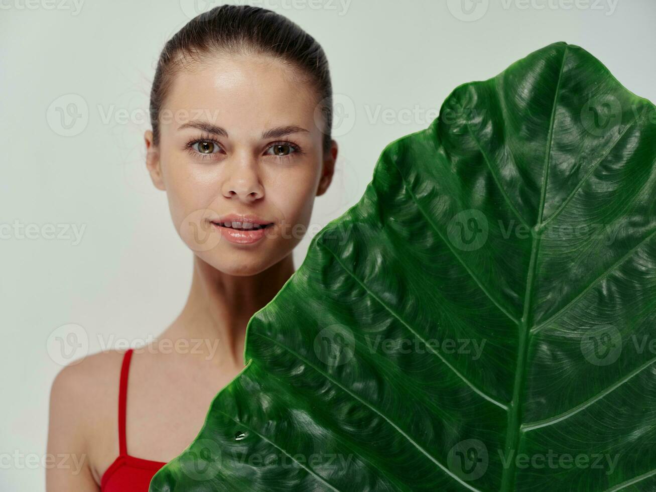 woman in a red swimsuit palm leaf Exotic attractive look light background photo