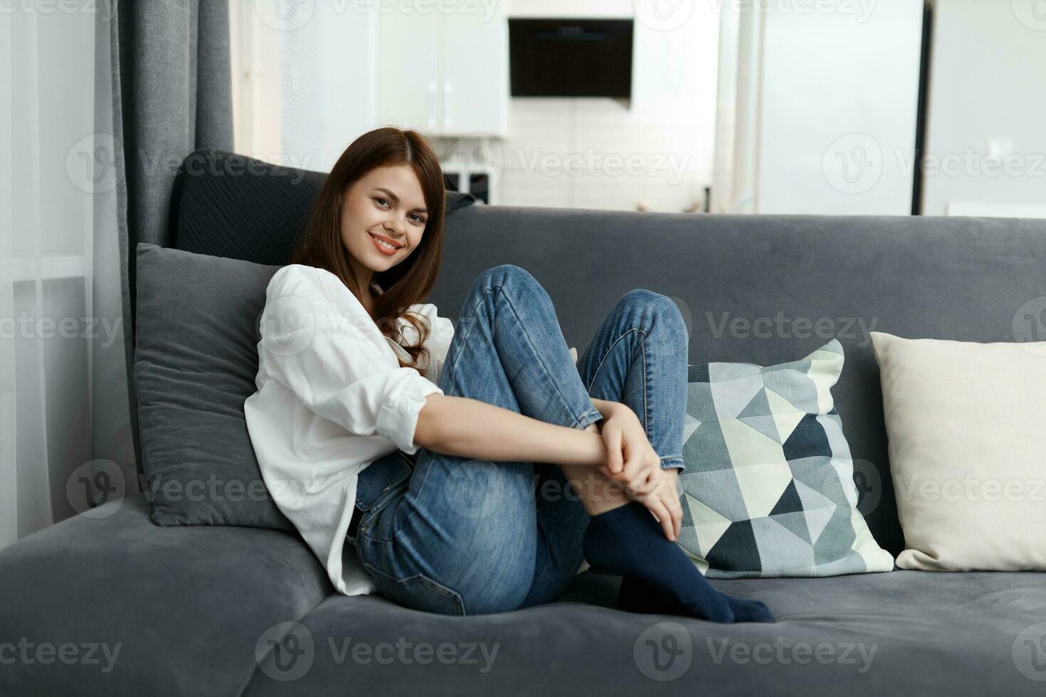 cheerful woman sitting on a sofa with raised legs flat rest photo