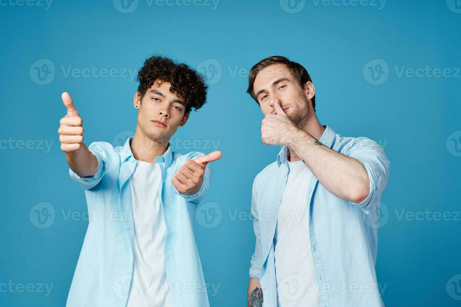 young guys in the same shirts and t-shirts are gesturing with their hands on a blue background friends photo