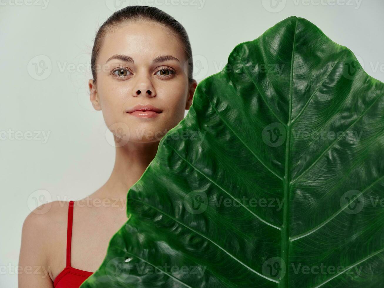 pretty woman in red swimsuit hiding behind palm leaf photo
