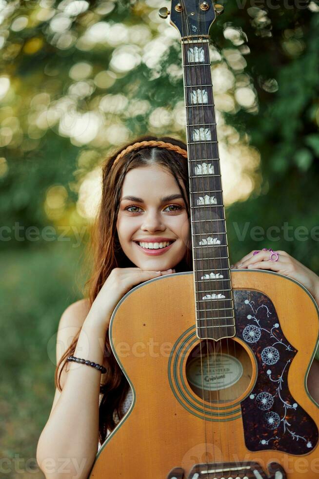 Young hippie woman with eco image smiling and looking into the camera with guitar in hand in nature on a trip photo