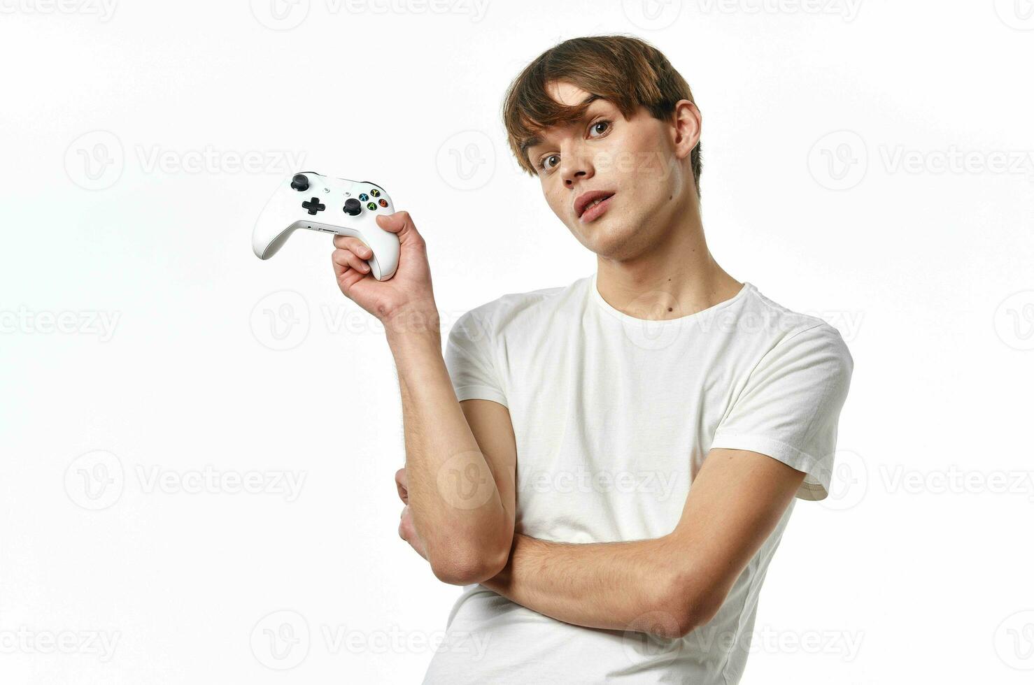 young guy in a white t-shirt Joystick in the hands of the game emotions light background photo