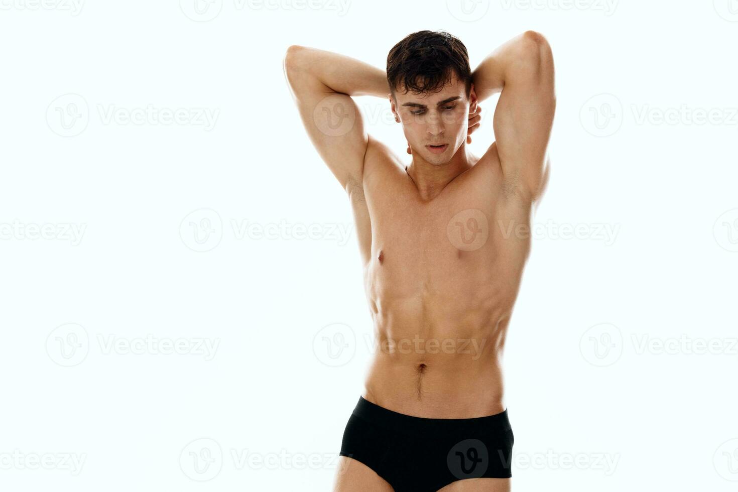 sporty man holding hands behind head workout macho light background photo