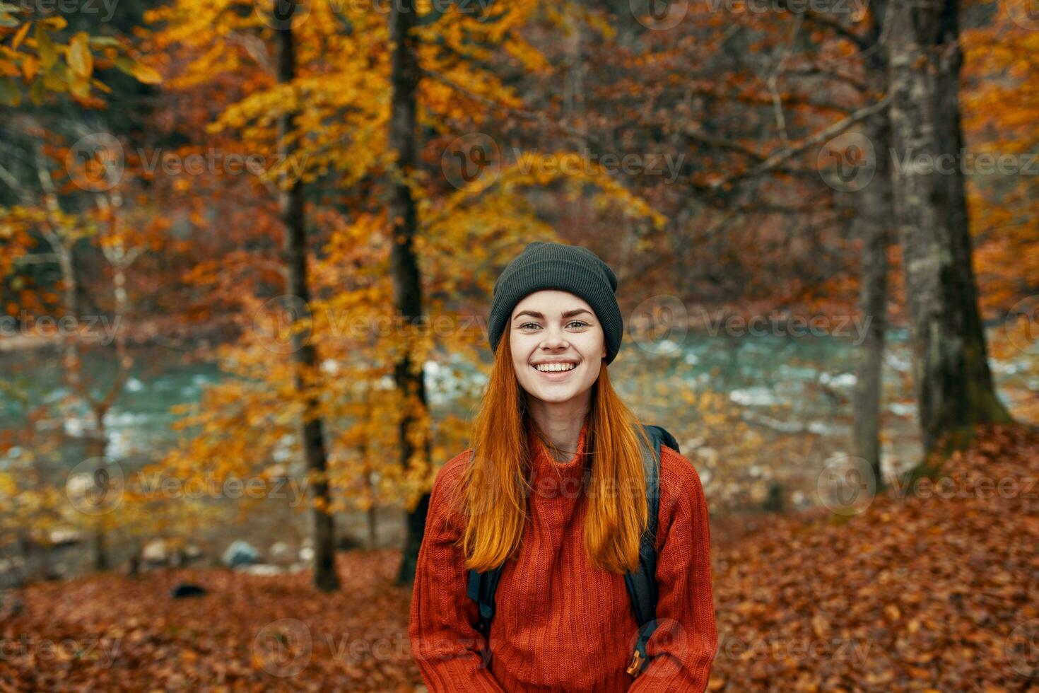 cheerful woman travels in the autumn forest in nature near the river and tall trees in the background photo