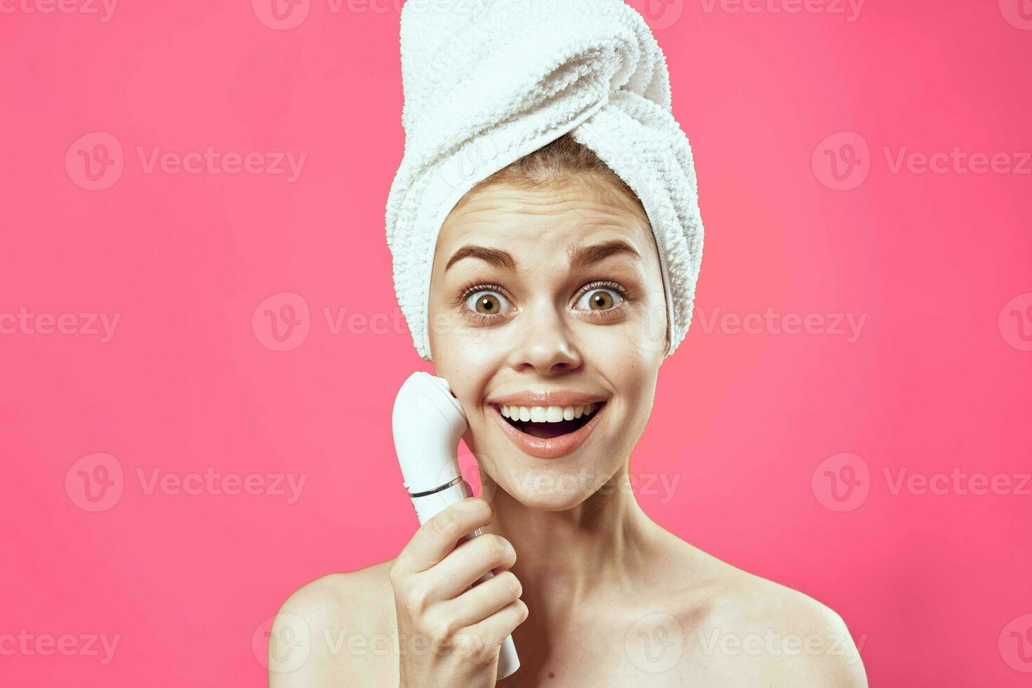 woman with towel on head naked shoulders skin care cosmetology pink background photo