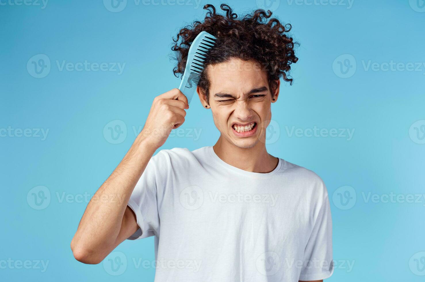 indignant guy combing hair with blue comb on isolated background cropped view photo