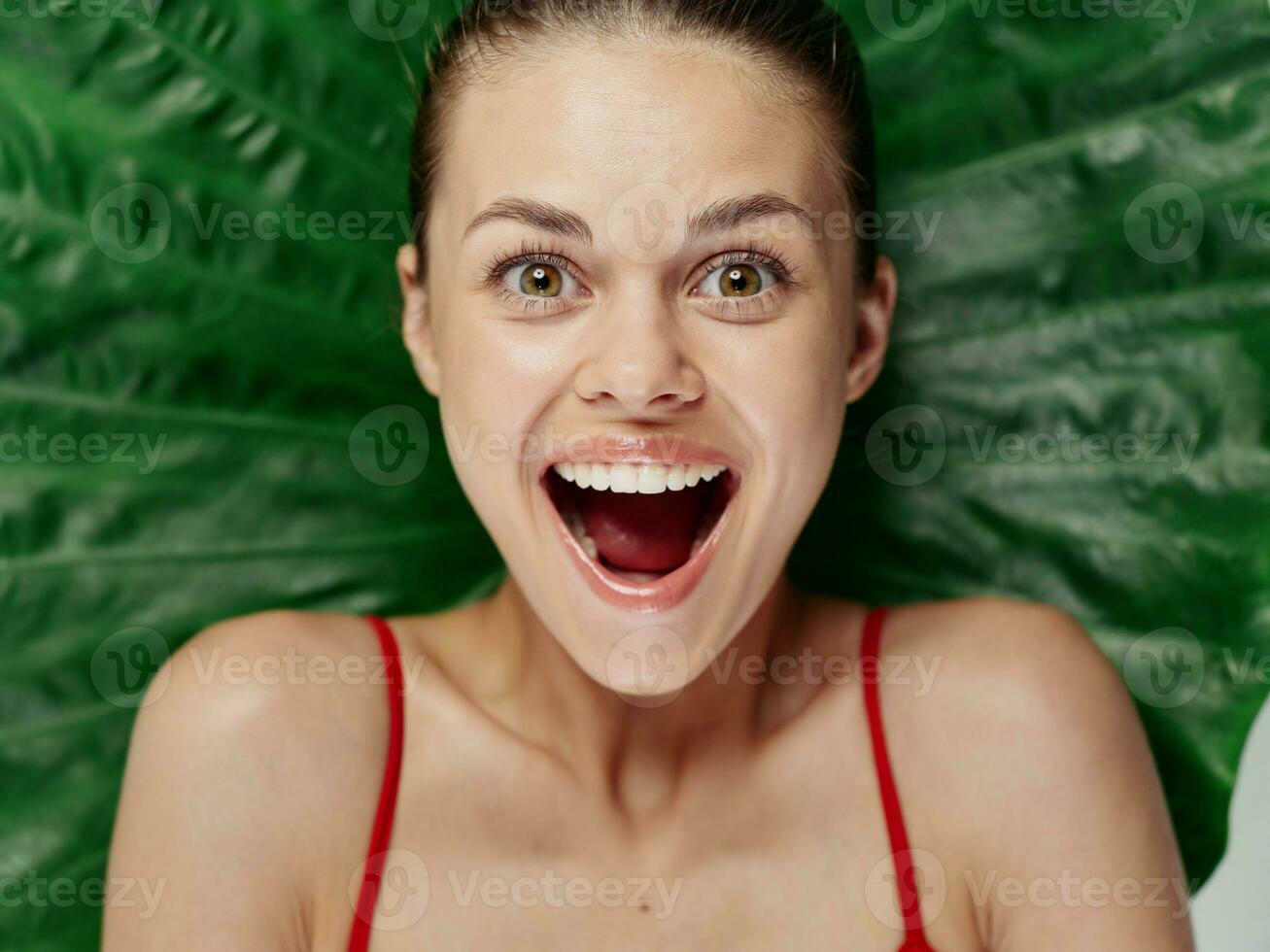 joyful woman in swimsuit with open mouth palm leaf behind head close-up photo