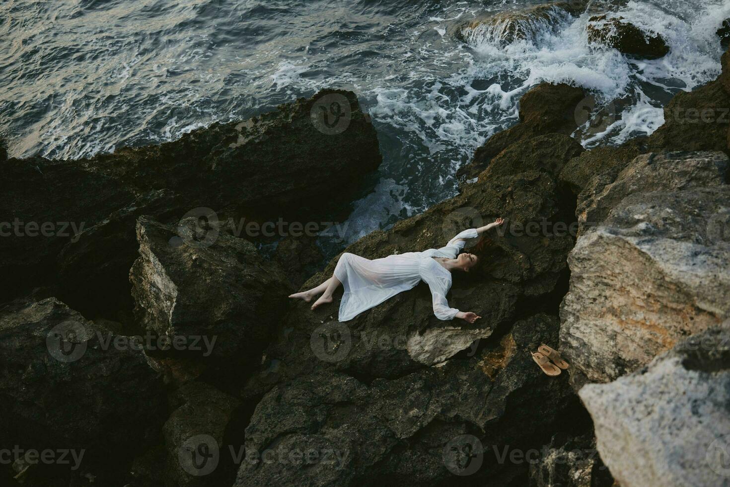 beautiful young woman lying on rocky coast with cracks on rocky surface Summer vacation concept photo