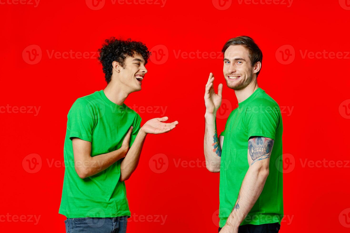 two men in green t-shirts stand next to communication Friendship red background photo