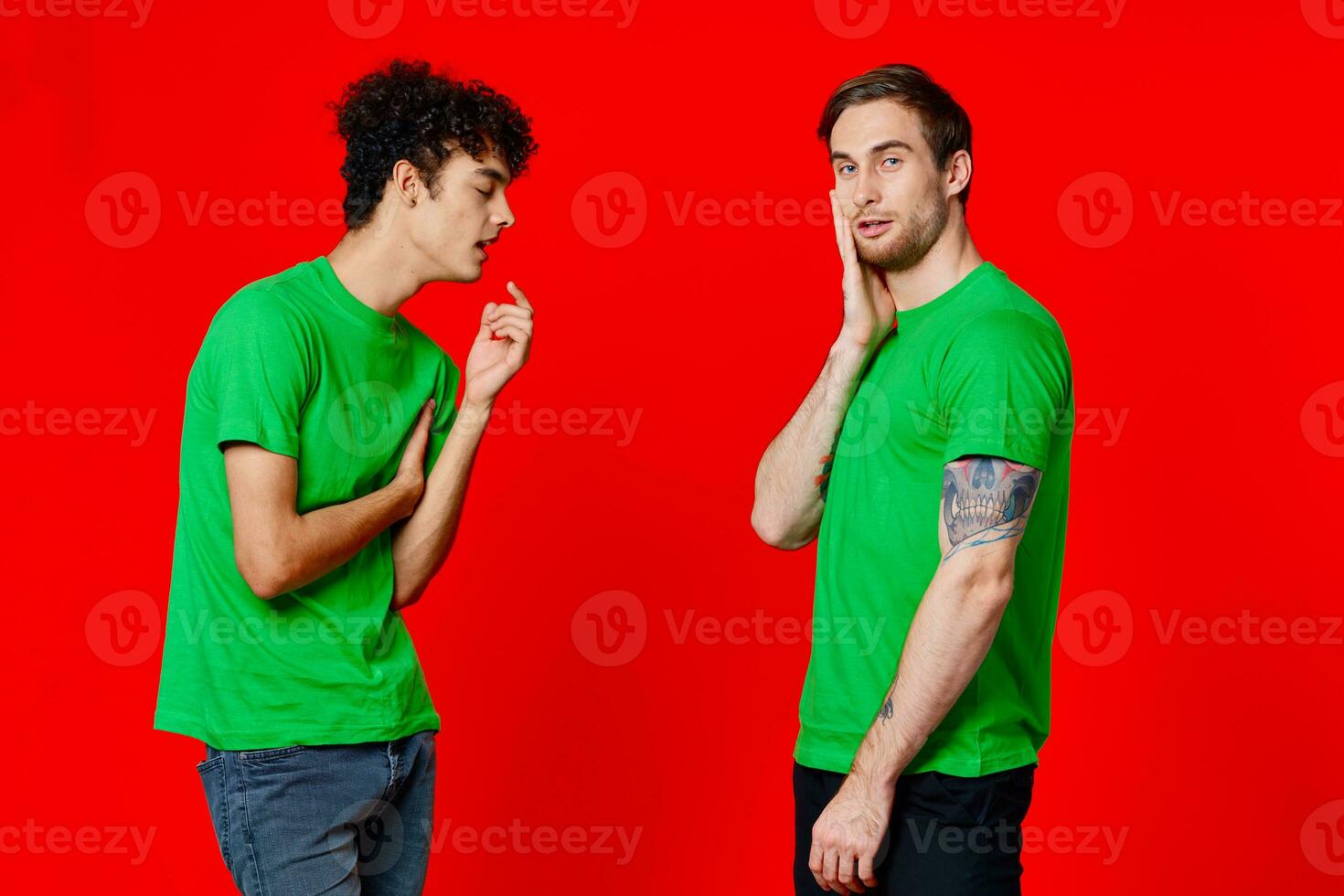 two men in green t-shirts stand next to communication Friendship red background photo