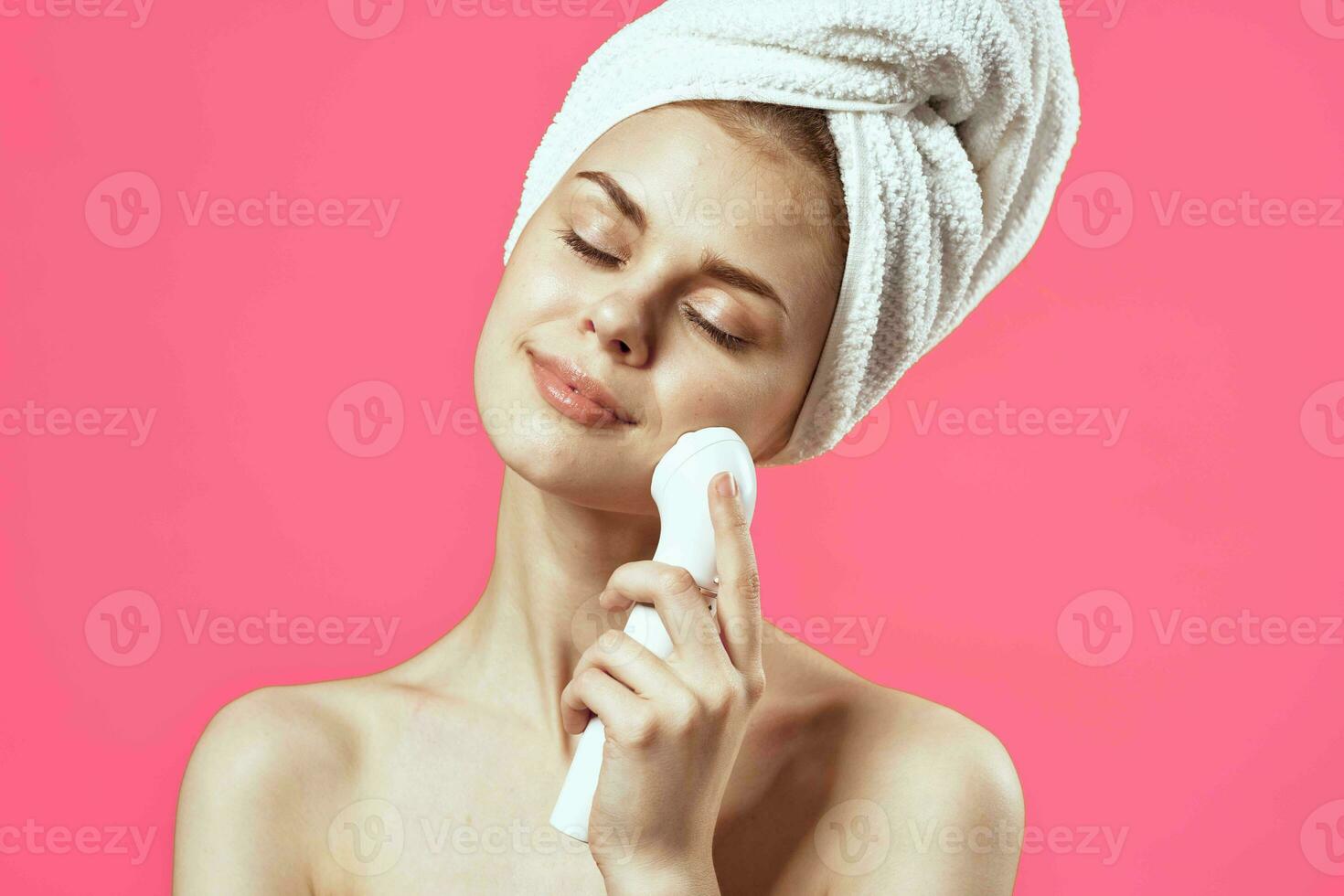 woman with bare shoulders and towel on head face massager photo