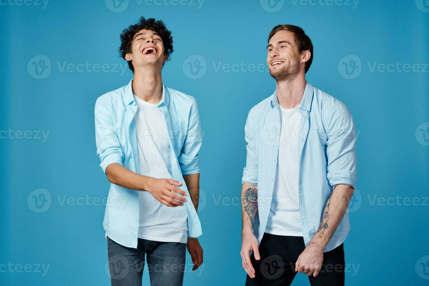 curly guy in a blue shirt and a blond man on a blue background communication friends fun photo