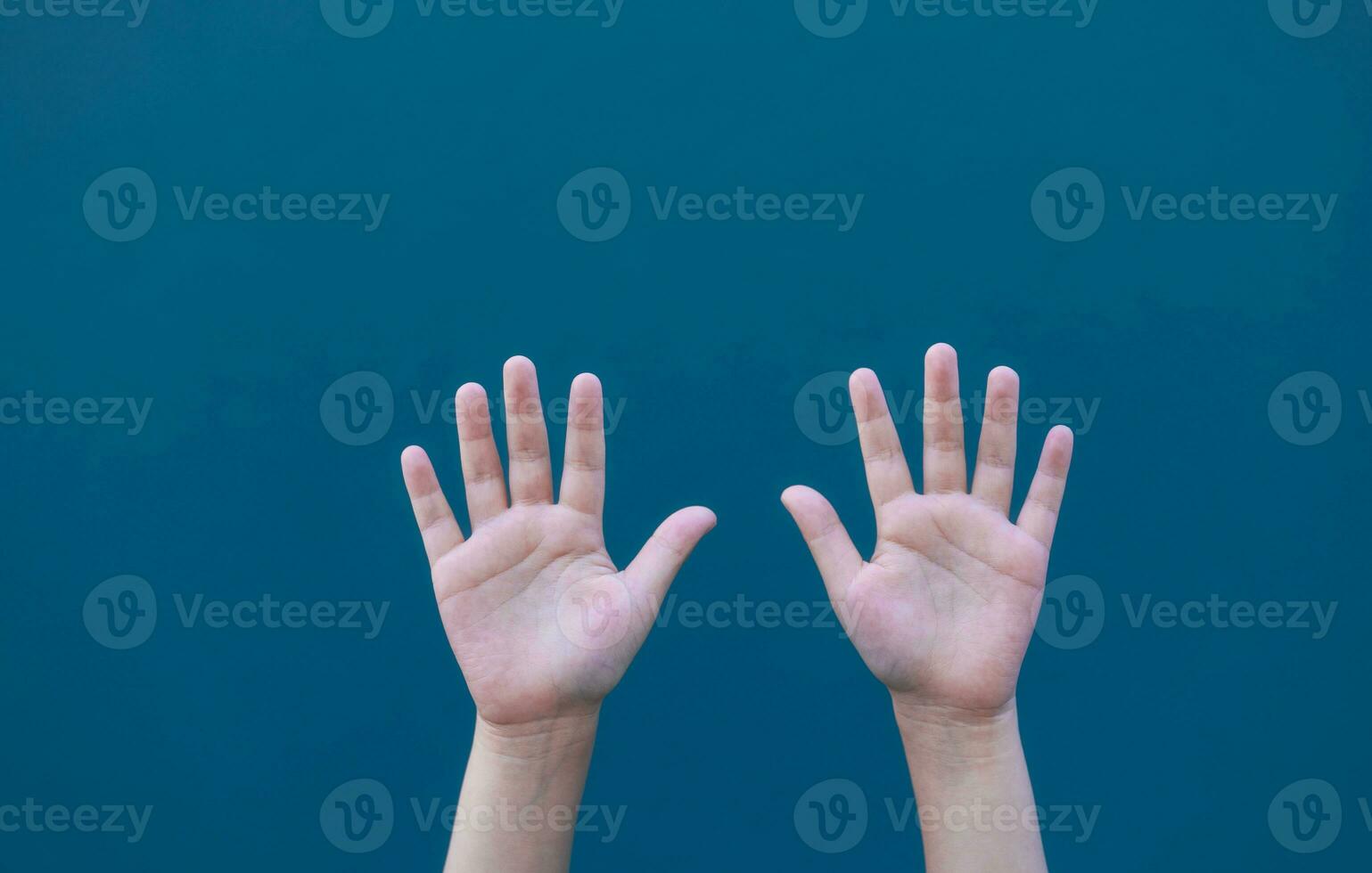 hands rise up with blue wall blurred background, helping hand concept, girl hand rise up photo