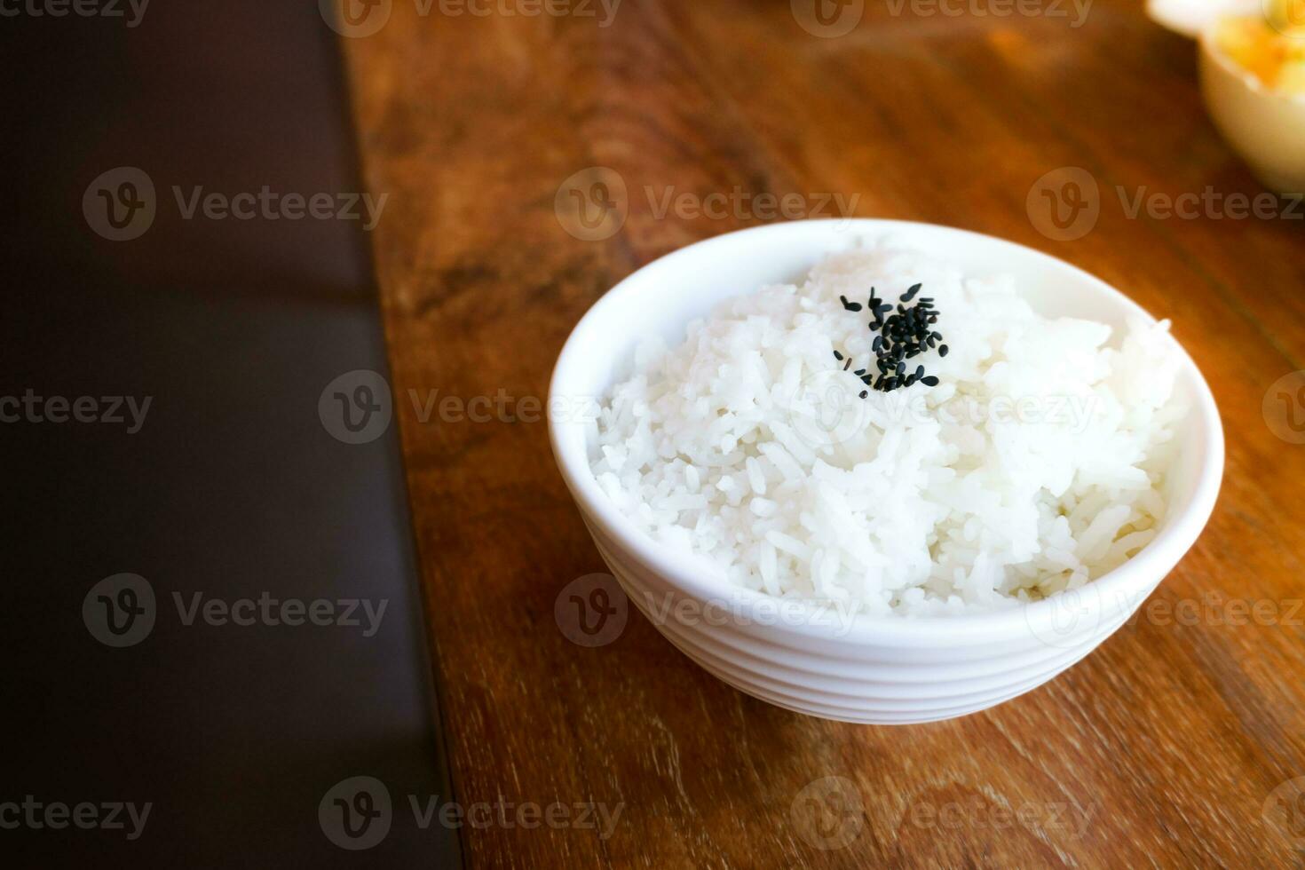 Rice in white cup on wood background and black sesame photo