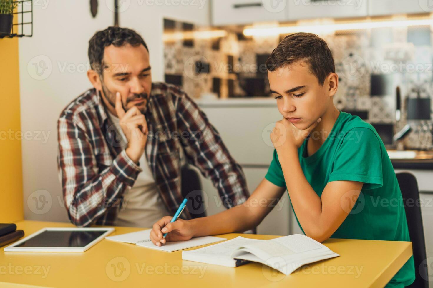 Father is helping his son with learning. They are doing homework together. photo