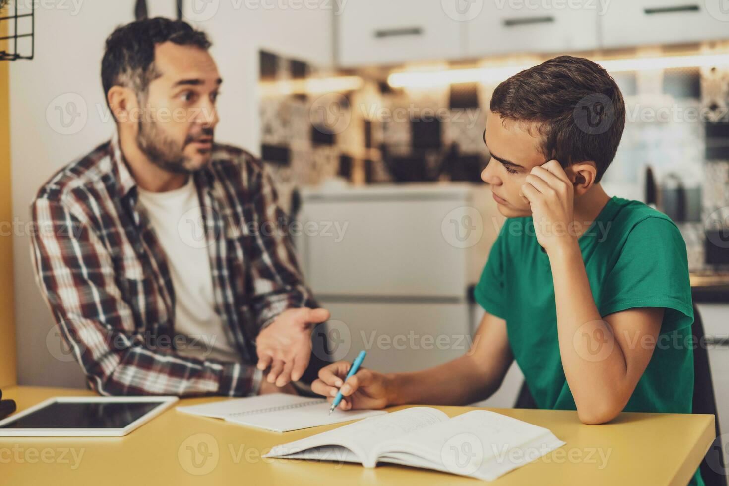 Father is helping his son with learning. They are doing homework together. photo