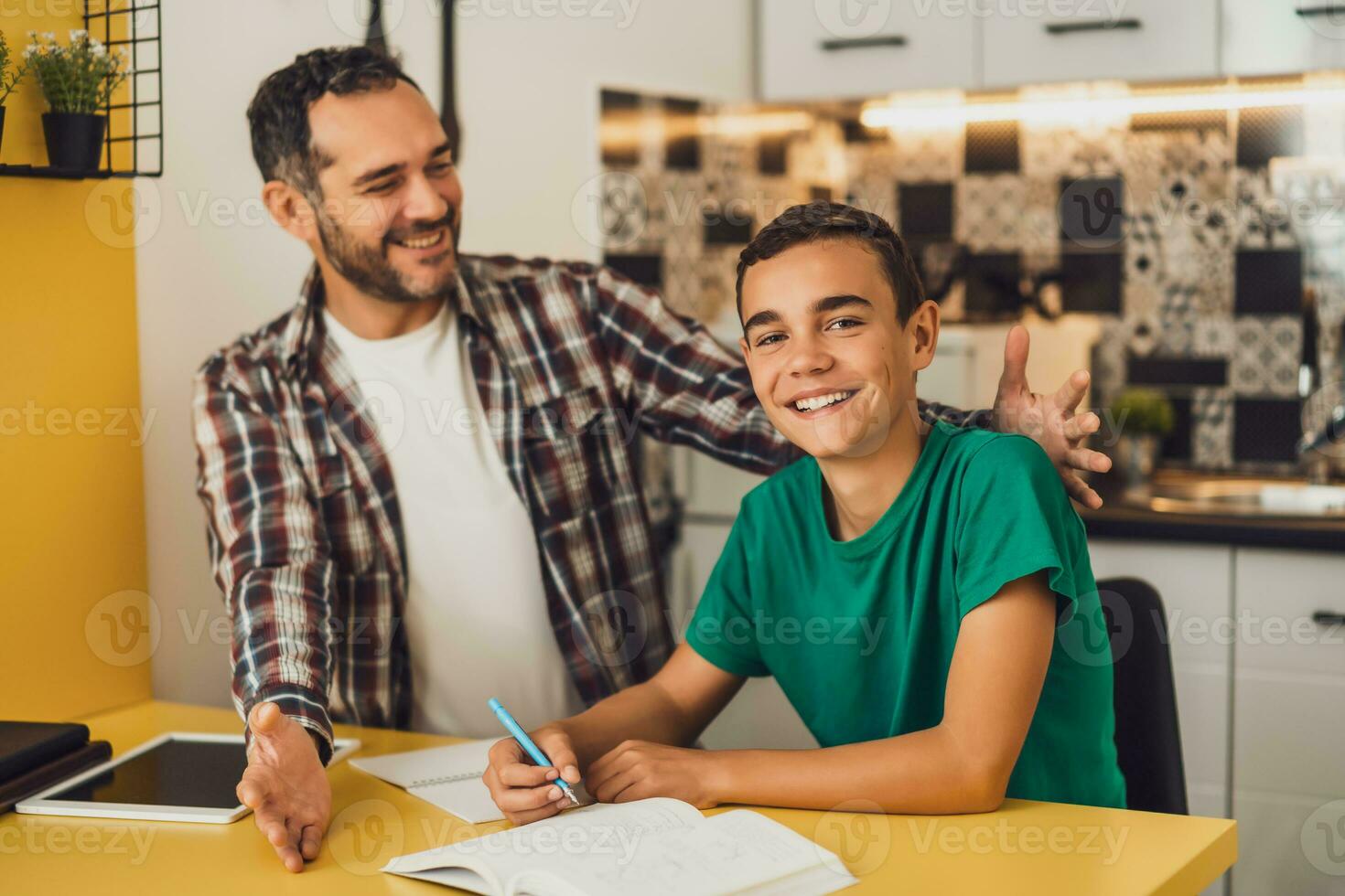 Father is helping his son with learning. They are doing homework together. photo