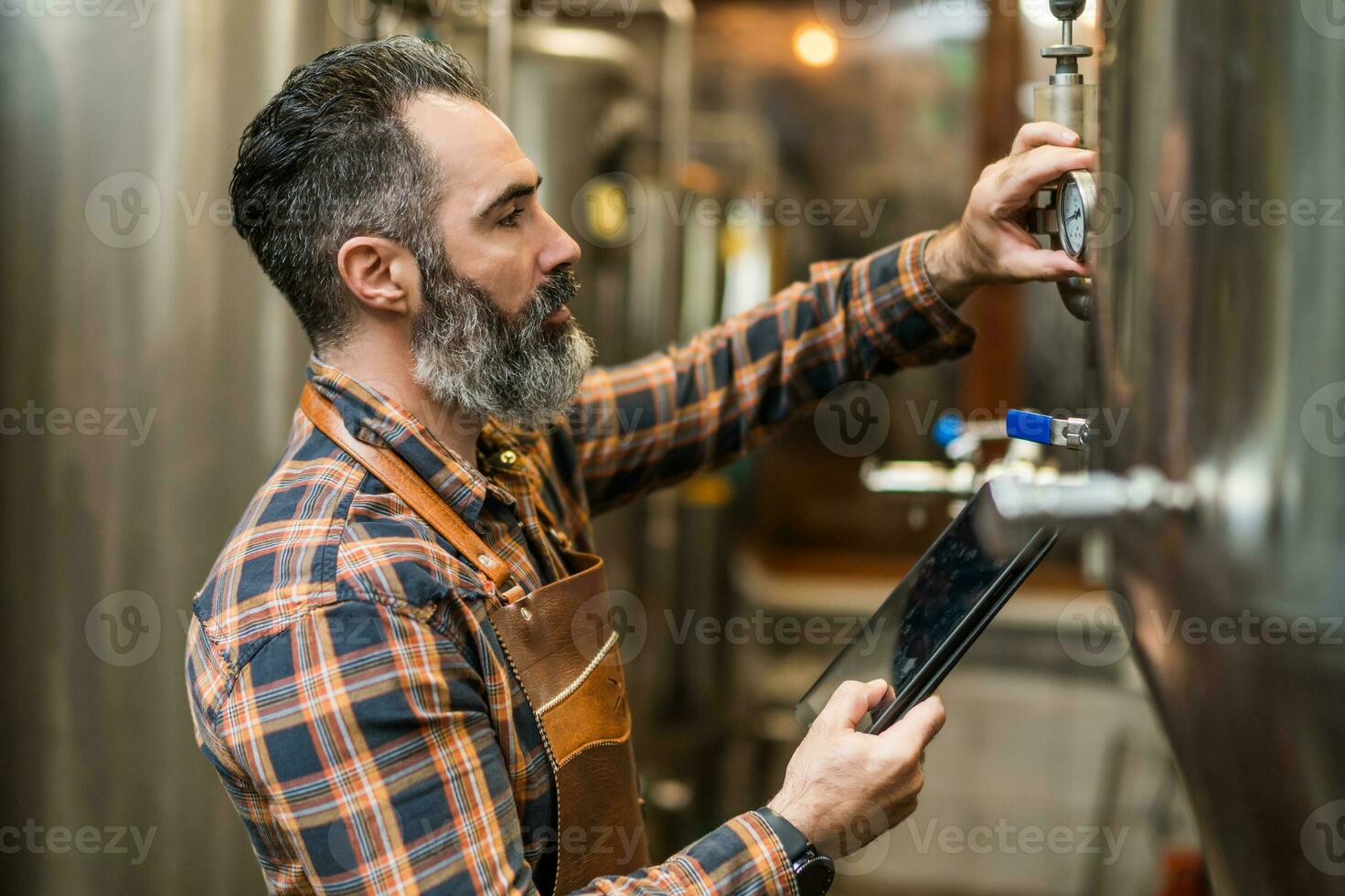 Man is working at craft beer factory. He is operating machinery in brewery. Small family business, production of craft beer. photo