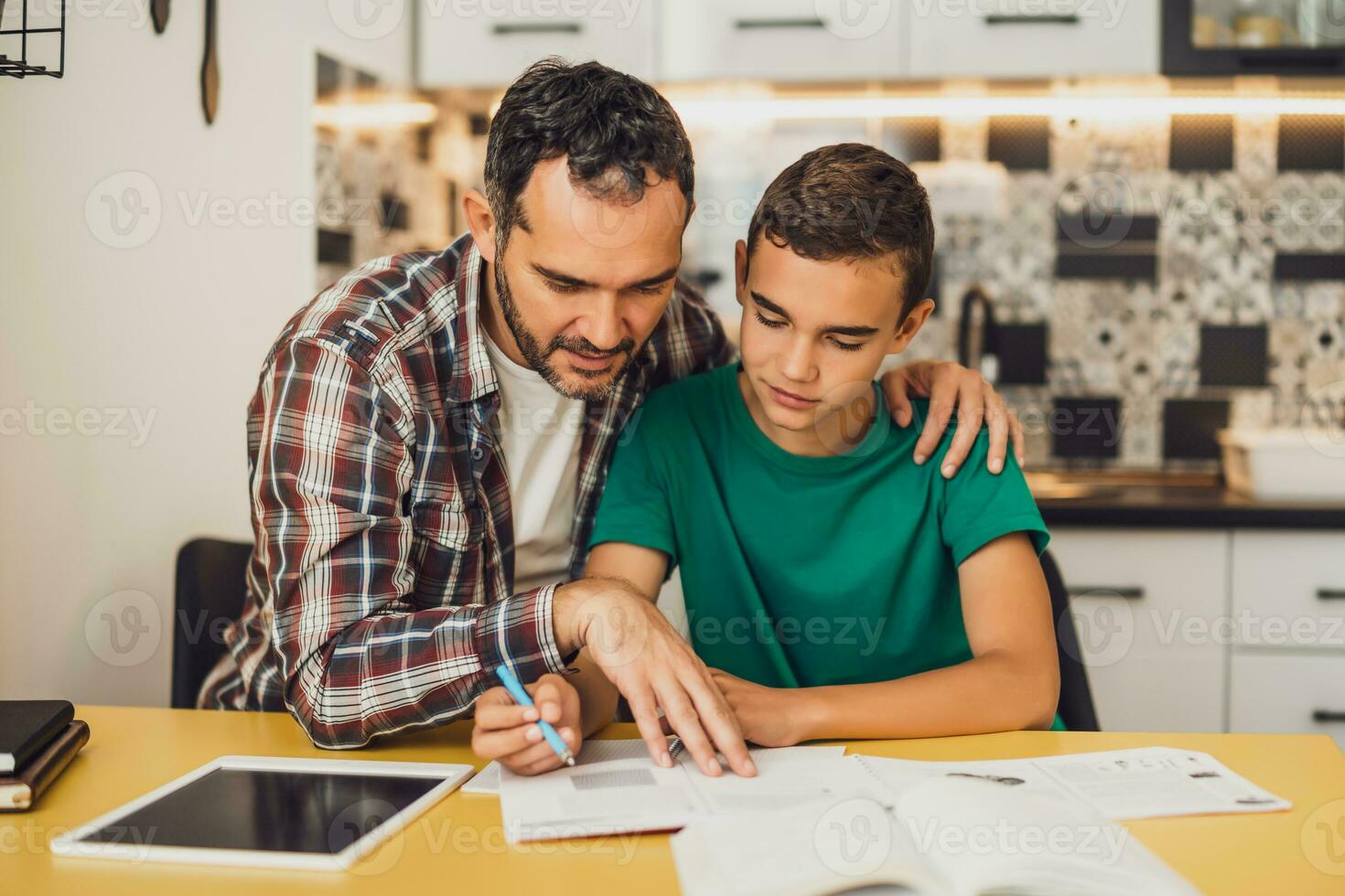 Father is helping his son with learning. They are doing homework together. photo
