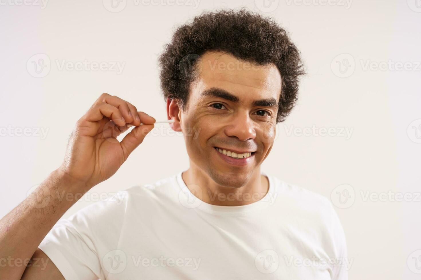 Multiracial man using cotton swabs on his ear. Self care concept. photo