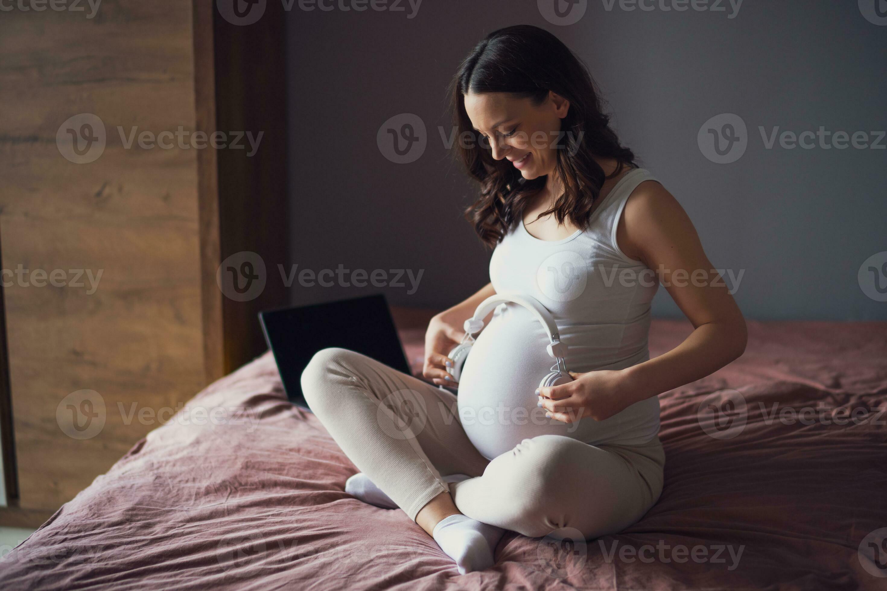 Pregnant woman with headphones on her belly at home. 23255303 Stock Photo  at Vecteezy