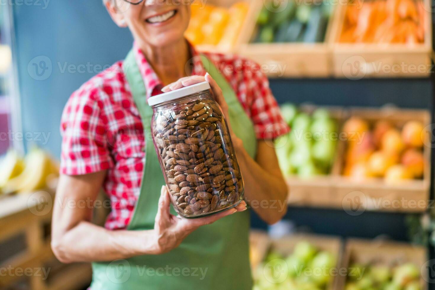 mujer trabajos en frutas y vegetales tienda. ella es participación tarro con Almendras. foto