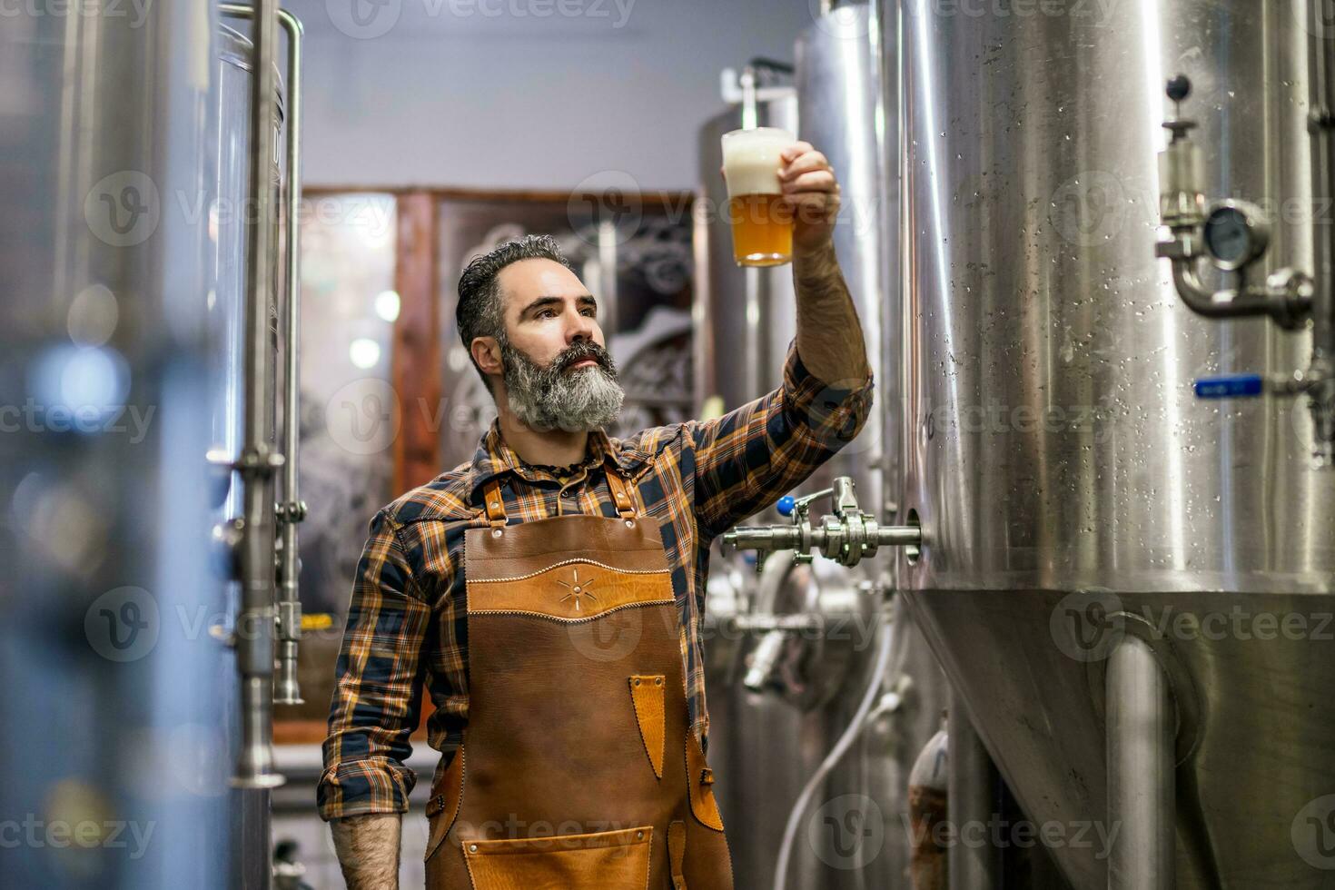 Man is working at craft beer factory. He is operating machinery in brewery. Small family business, production of craft beer. photo