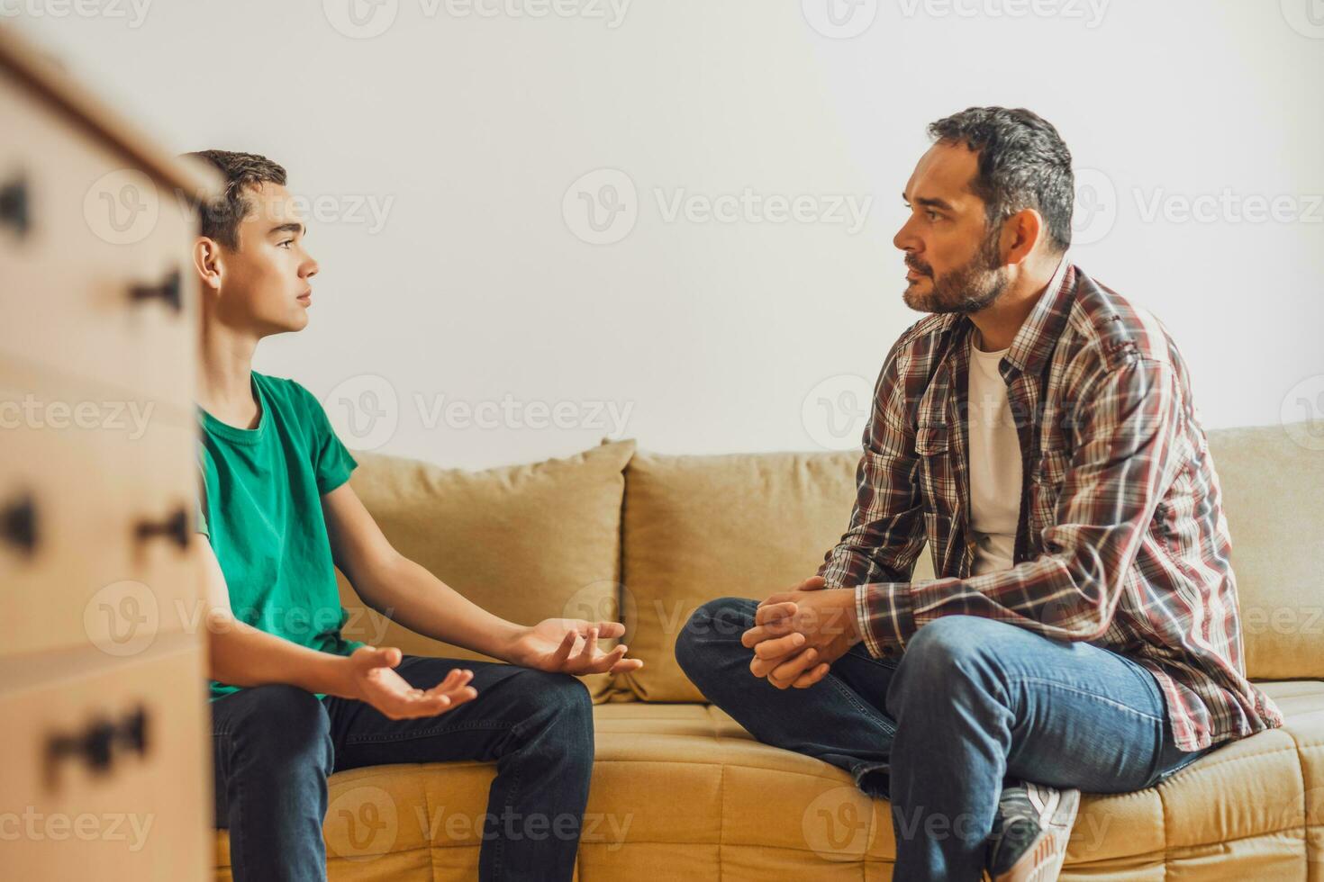 Portrait of frustrated father and son arguing at home. photo