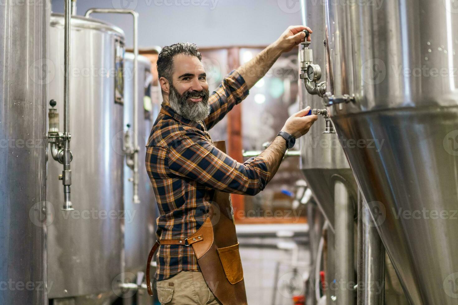 hombre es trabajando a arte cerveza fábrica. él es operando maquinaria en cervecería. pequeño familia negocio, producción de arte cerveza. foto