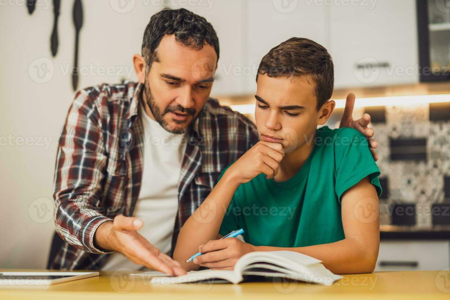 Father is helping his son with learning. They are doing homework together. photo