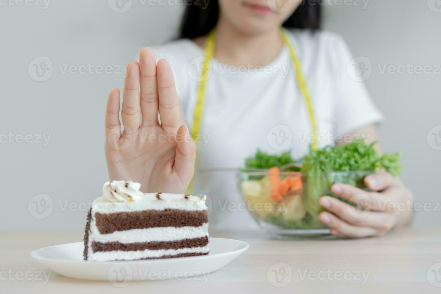 Diet, Dieting asian young woman using hand push out, deny chocolate cake or sweet taste, dessert food, choose eat green salad vegetables when hungry. Nutritionist of healthy, nutrition of weight loss. photo