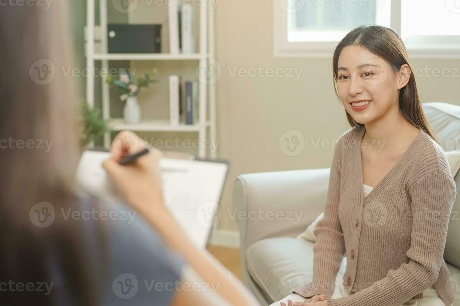 Psychology, depression. smile asian young woman patient  mental explained symptom with psychologist, psychiatrist while doctor woman taking notes at clinic. Encouraging, therapy. photo