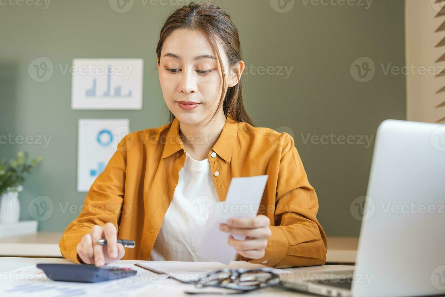 Asian young employee, business woman calculate tax income and expenses, bills, credit card for payment or payday on table at home office. Financial, finance people concept. photo