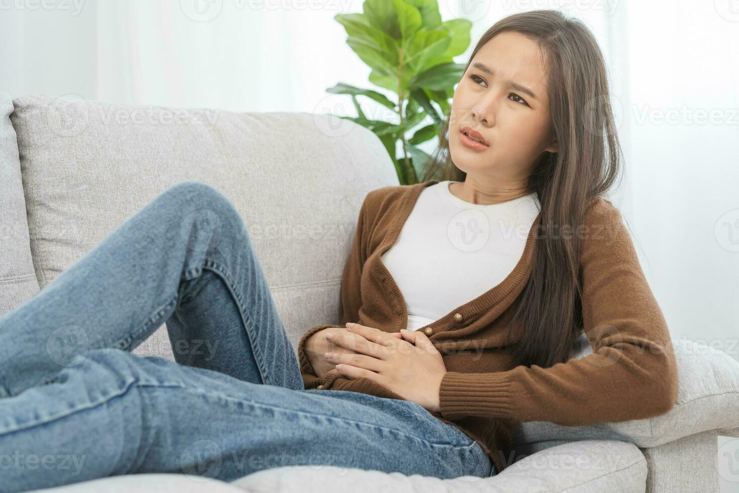 Flatulence asian young woman, girl hand in stomach ache, suffer from food poisoning, abdominal pain and colon problem, gastritis or diarrhoea. Patient belly, abdomen or inflammation, concept. photo