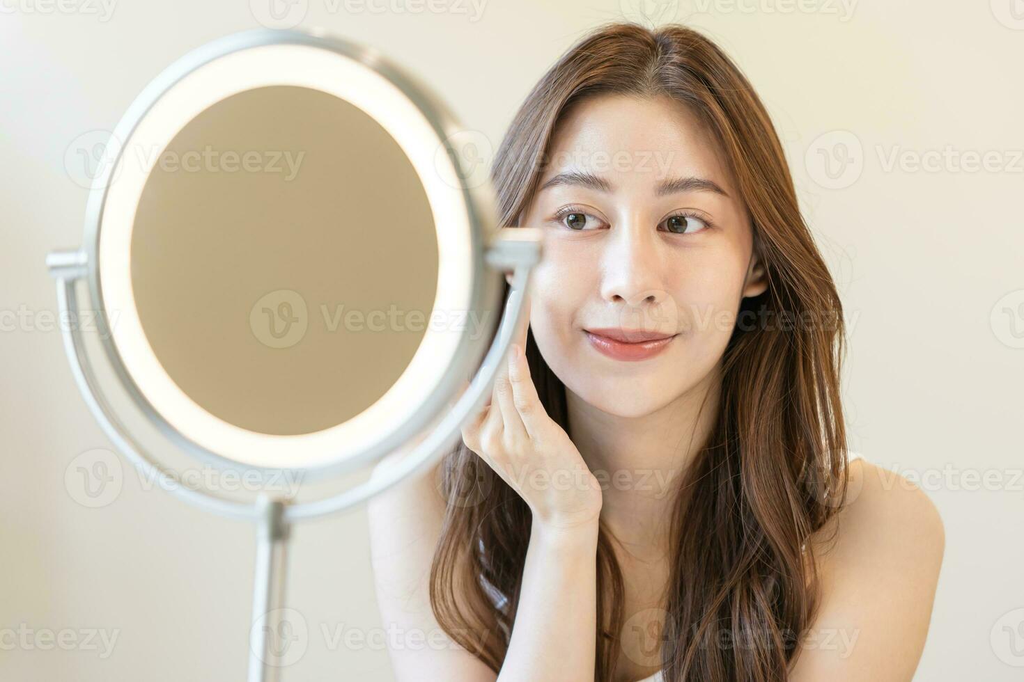 Fresh, nice healthy skin, beautiful of asian young woman, girl looking at mirror, touching her face with before make up cosmetic routine at home. Female look with natural fashion style, Facial Beauty. photo