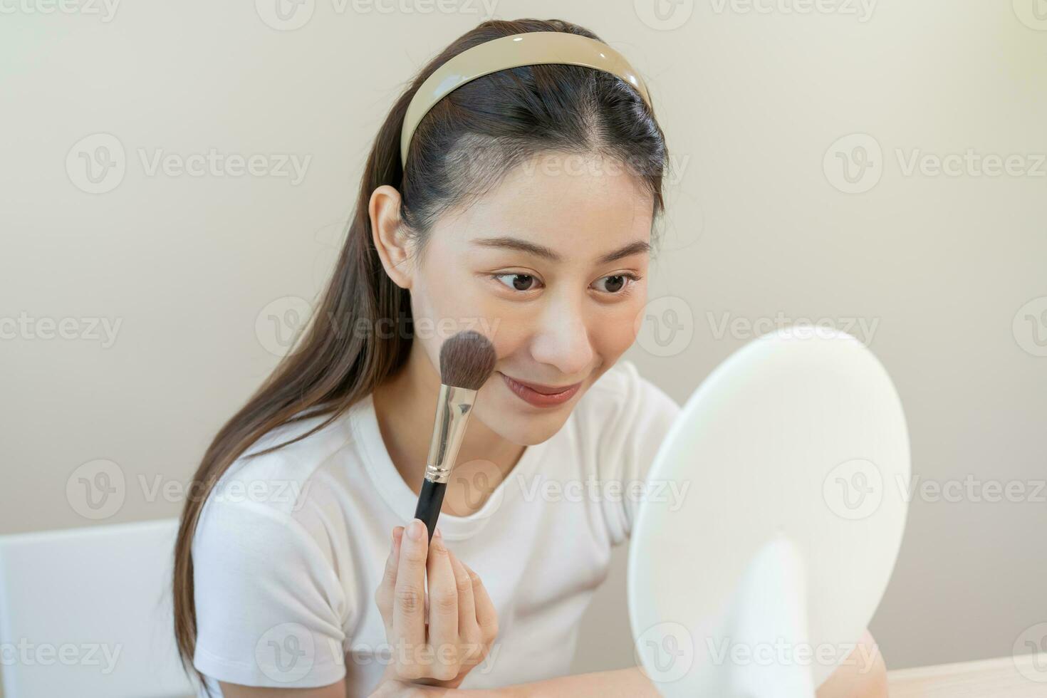 contento rutina belleza concepto, bonito asiático joven mujer, niña hacer arriba cara por aplicando polvo Fundación por cepillo alrededor rostro, mirando a el espejo a hogar. hembra Mira con natural Moda estilo. foto