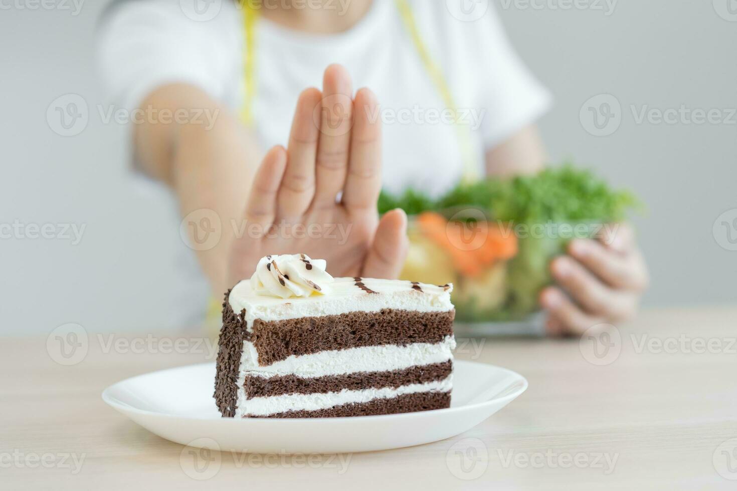 Diet, Dieting asian young woman using hand push out, deny chocolate cake or sweet taste, dessert food, choose eat green salad vegetables when hungry. Nutritionist of healthy, nutrition of weight loss. photo