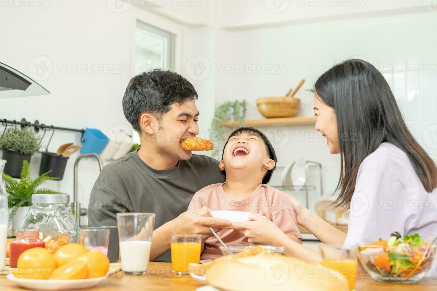 Happy refreshment family breakfast in morning, asian young parent father, mother and little cute boy, child having meal in kitchen eating together at home. Cheerful, enjoy cooking people. photo