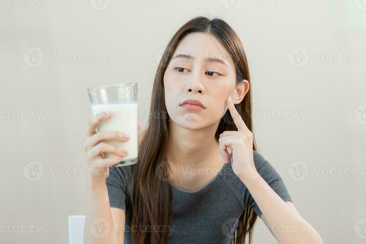 Allergy asian young woman, girl looking, holding glass of milk, face in