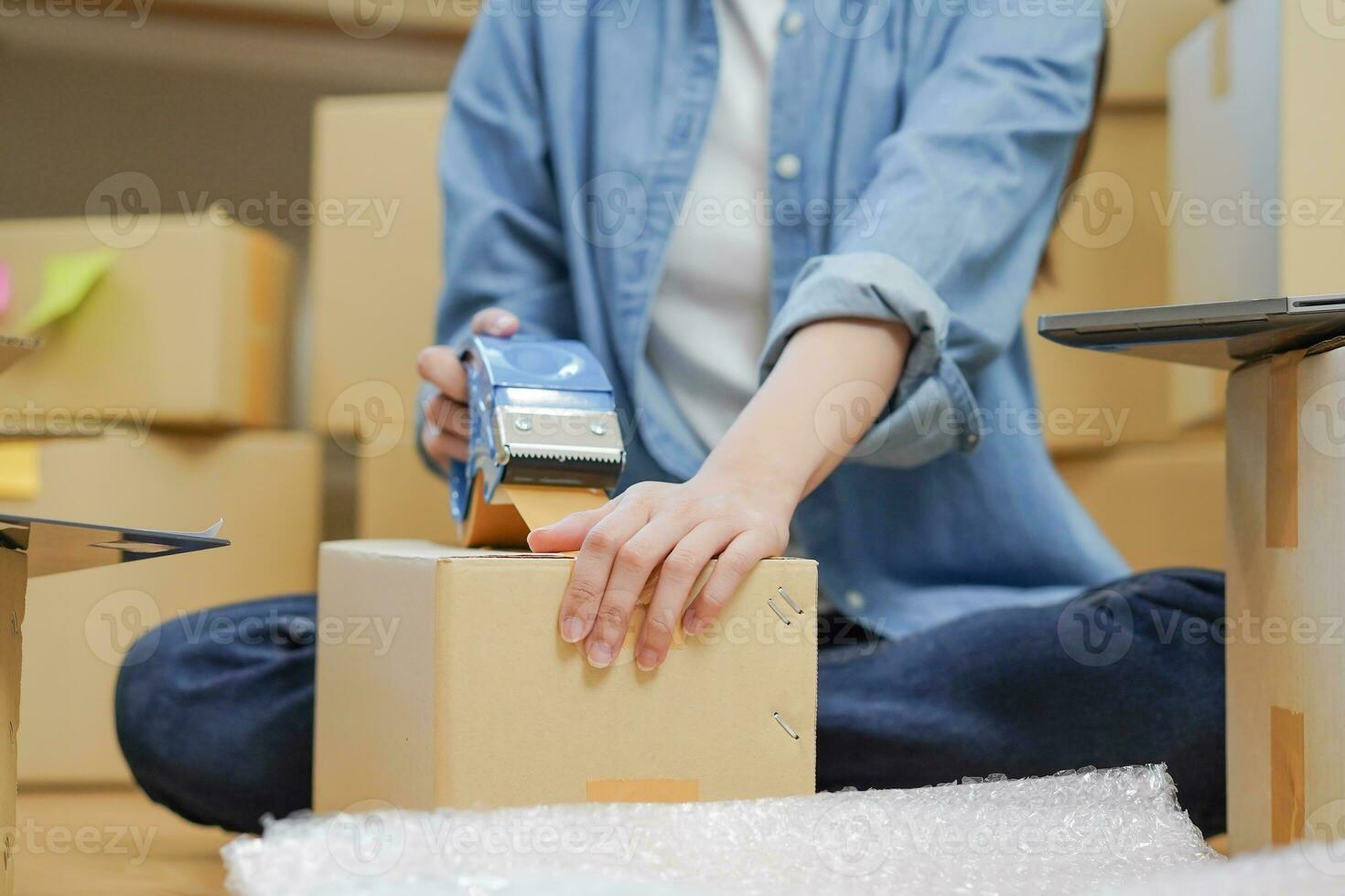Small business entrepreneur SME, asian young woman,girl owner packing product, checking parcel for delivery to customer, using scotch tape to seal the box, working at home. Merchant online, e commerce photo