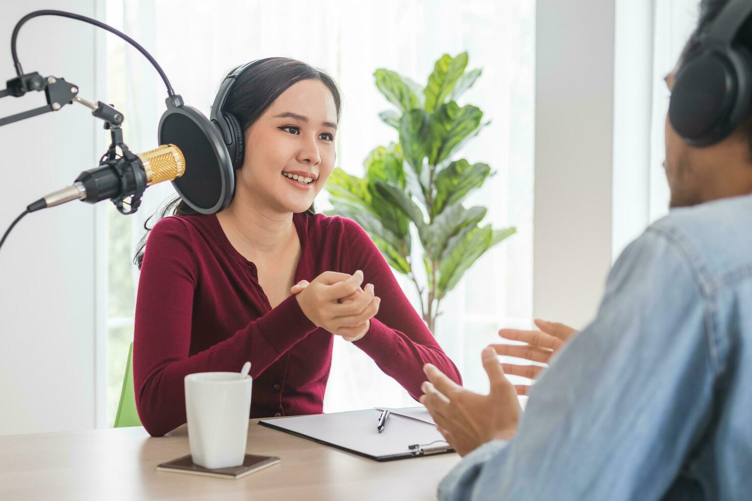 Smile two asian young woman, man radio hosts in headphones, microphone while talk, conversation, recording podcast in broadcasting at studio together. Technology of making record audio concept. photo