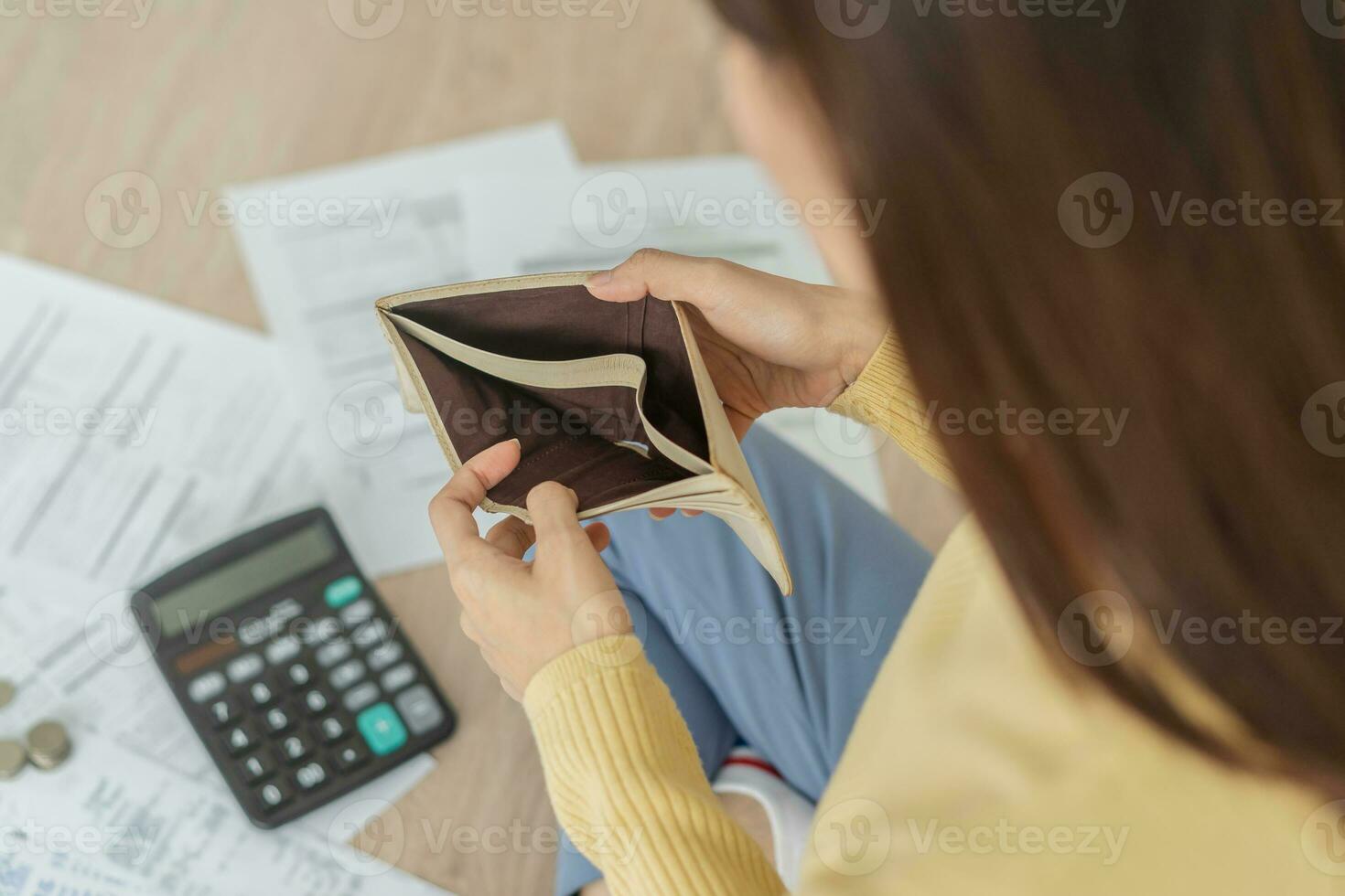 Top view owe asian woman, female sitting on floor stressed and confused by calculate expense from invoice or bill, have no money to pay, mortgage or loan. Debt, bankruptcy or bankrupt concept. photo