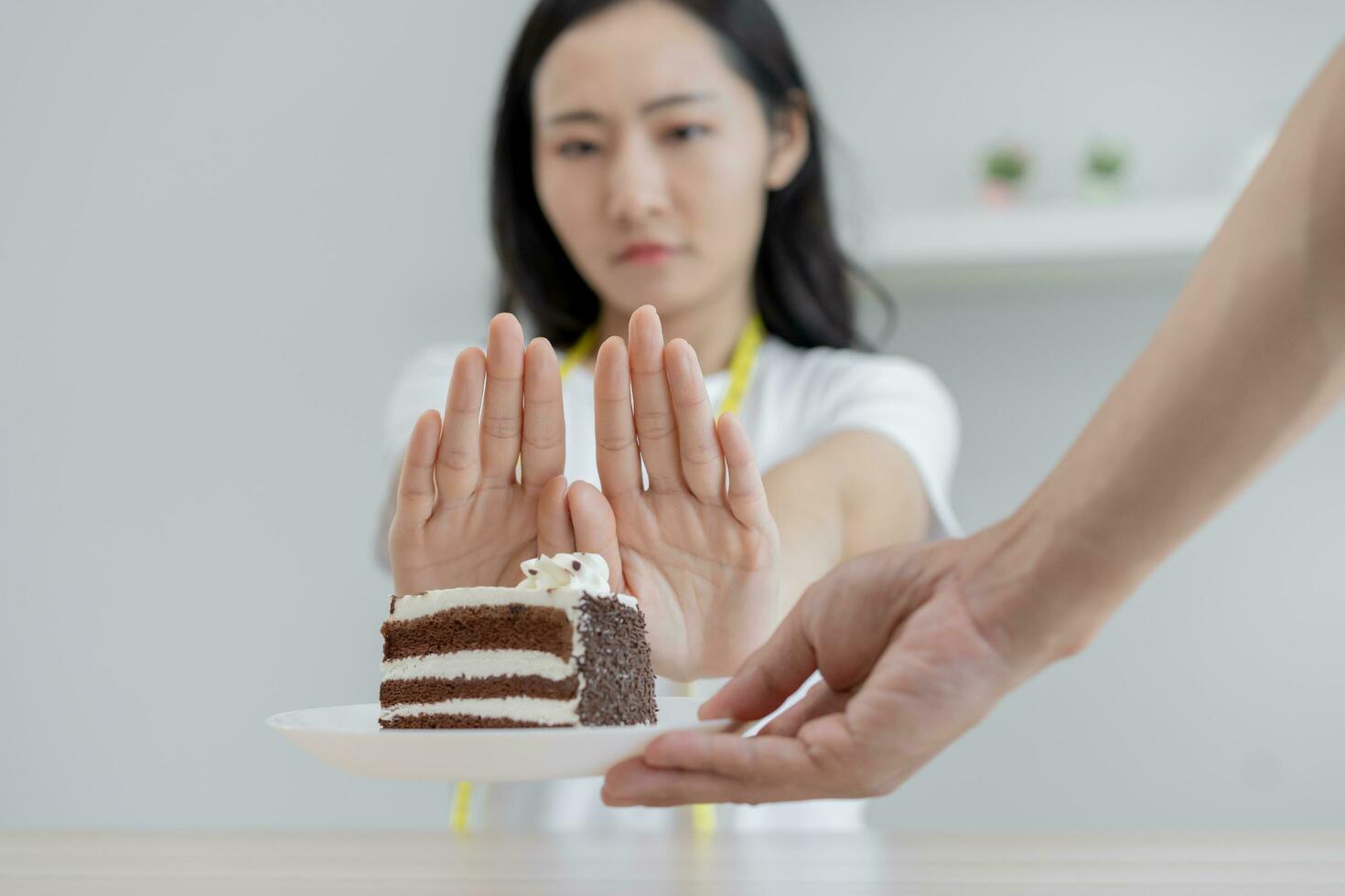 Diet, Dieting unhealthy asian young woman hand in push out, rejecting eat chocolate cake or sweet taste, fighting to keep it from getting fat when person bring to me. Healthy, nutrition of weight loss photo