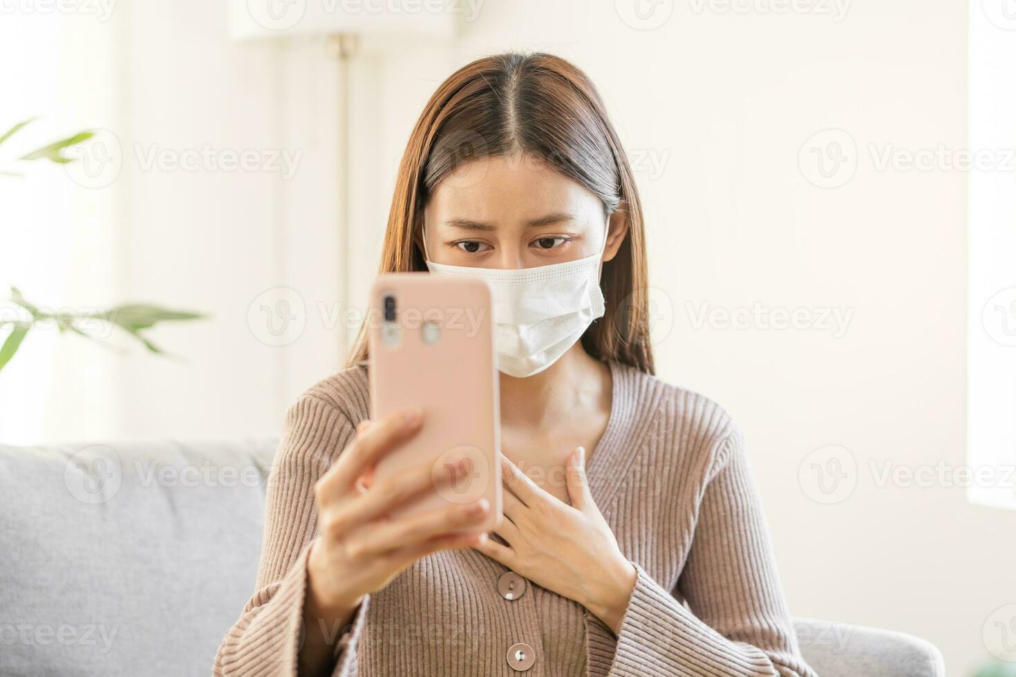 Sick, ill asian young woman, girl wearing mask with sore throat, headache have fever, flu and use smartphone consulting with doctor online, telehealth at home. Health care person on virus seasonal. photo